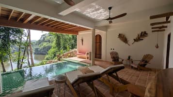 A pool area with lounge chairs, a ceiling fan, and a view of a natural landscape.