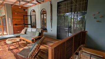 A modern interior with a wooden floor, a sofa, a dining table, and a staircase.