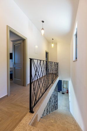 A staircase with a black metal railing, wooden flooring, and a light fixture. - Villa Edoardo by Istrabook (Vižinada)