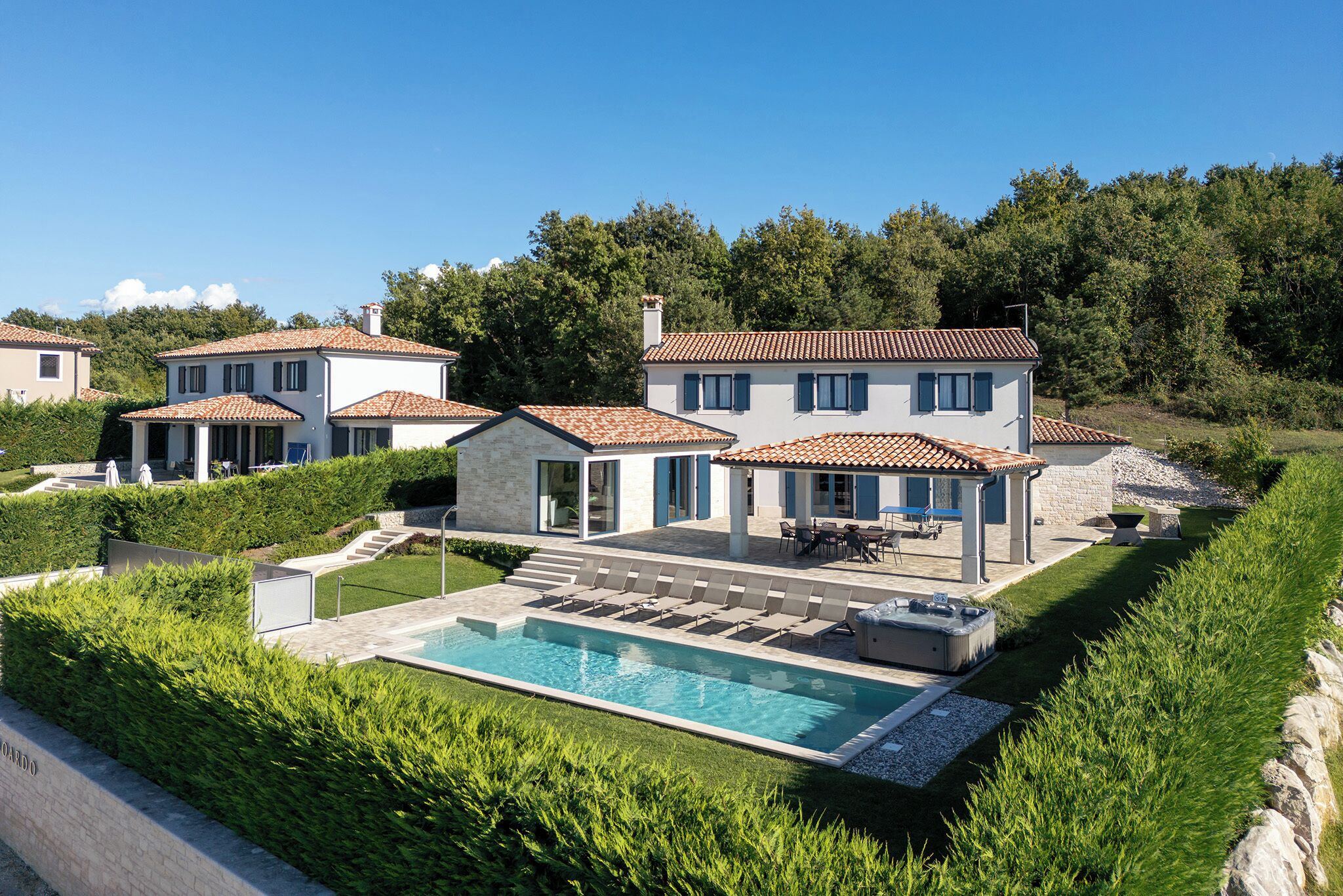 Ein Wohnhaus mit Schwimmbad, Sitzgelegenheiten im Freien und einem gepflegten Garten.