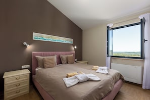 A bedroom with a bed, bedside tables, a nightstand, a painting, and a window with curtains. - Villa Edoardo by Istrabook (Vižinada)