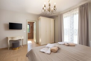 A hotel room with a bed, a desk, a wardrobe, a TV, and a chandelier. - Villa Edoardo by Istrabook (Vižinada)