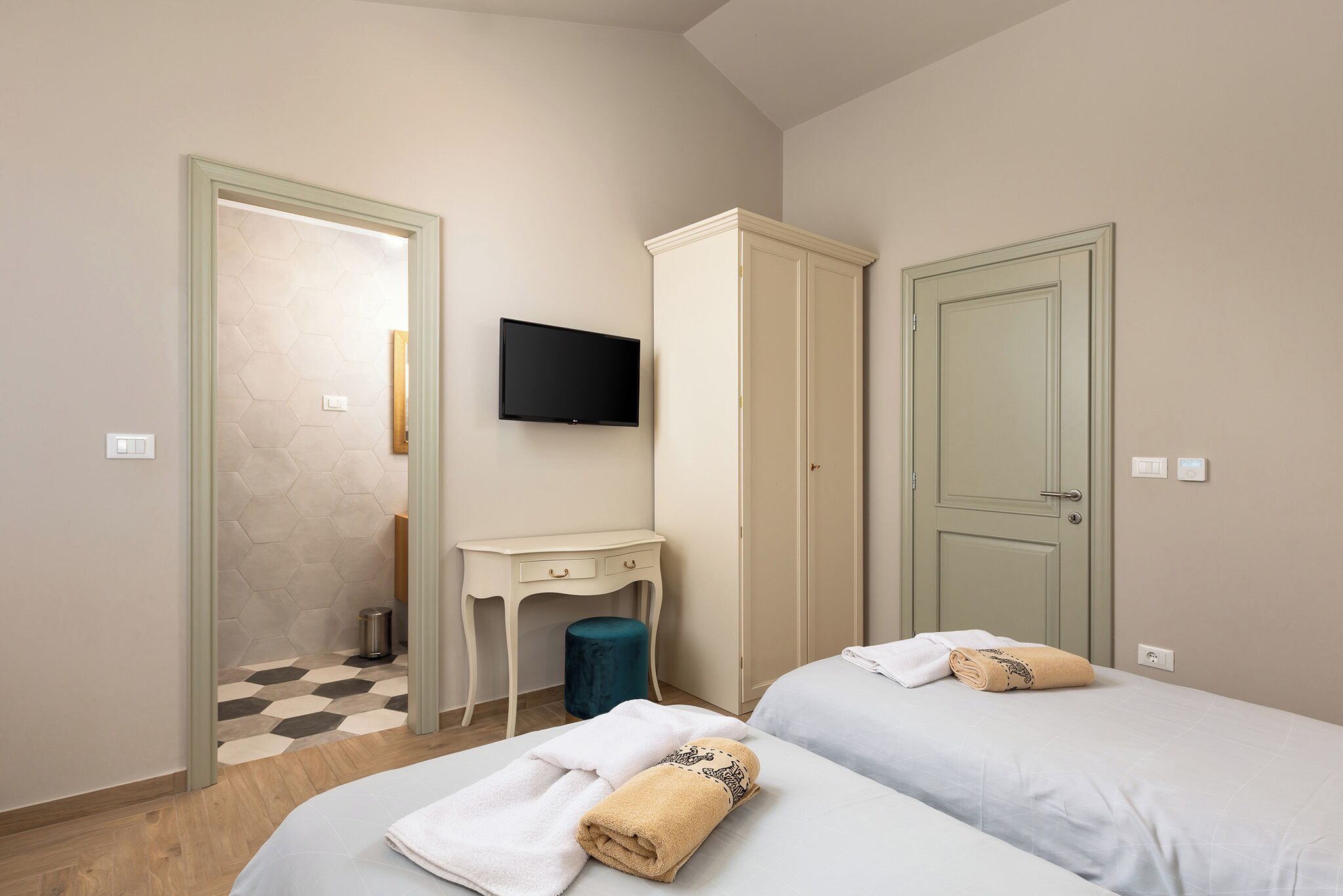 Habitación de hotel con dos camas, un escritorio, televisor y armario.
