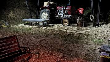A covered outdoor area with a tractor, a bench, and a campfire.