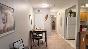 Un pasillo con comedor, cocina y una puerta que da a otra habitación.