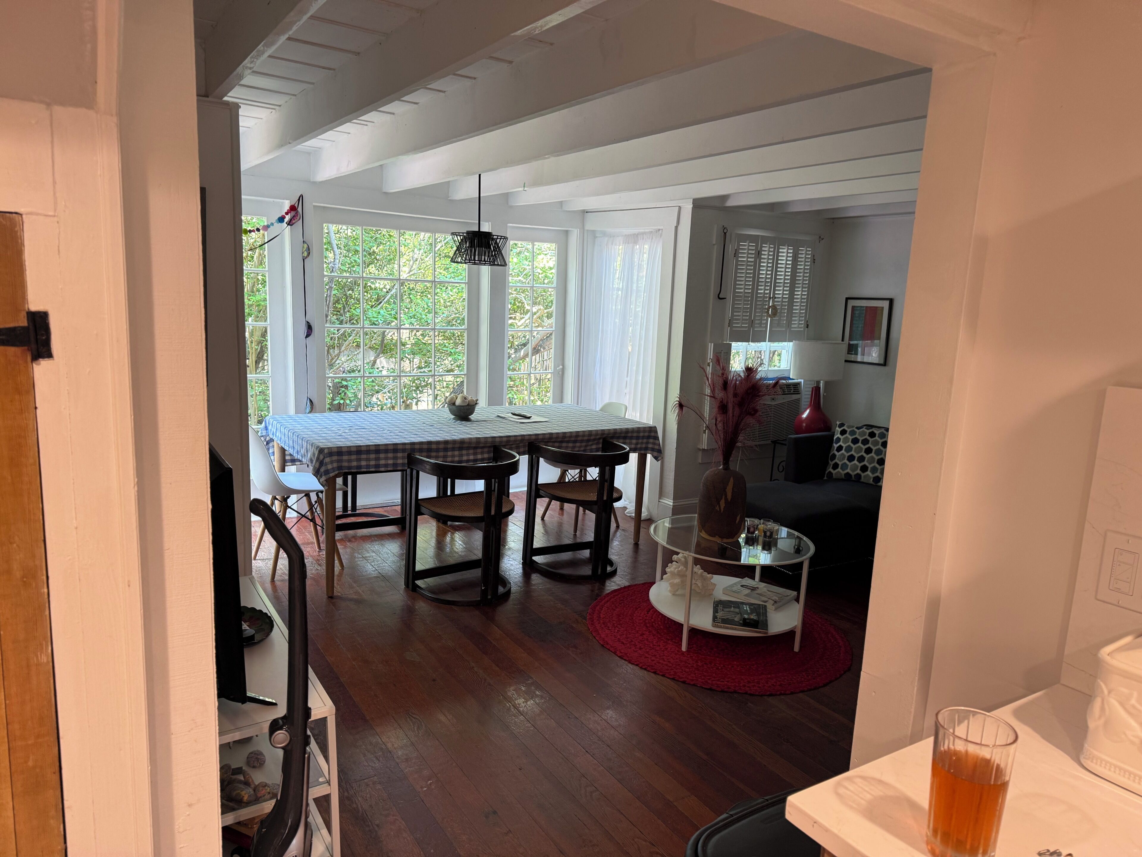 Un coin repas avec une table et des chaises, une table basse en verre et un tapis rouge.