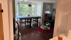 A dining area with a table and chairs, a glass coffee table, and a red rug.