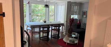 Un comedor con una mesa y sillas, una mesa de centro de vidrio y una alfombra roja.