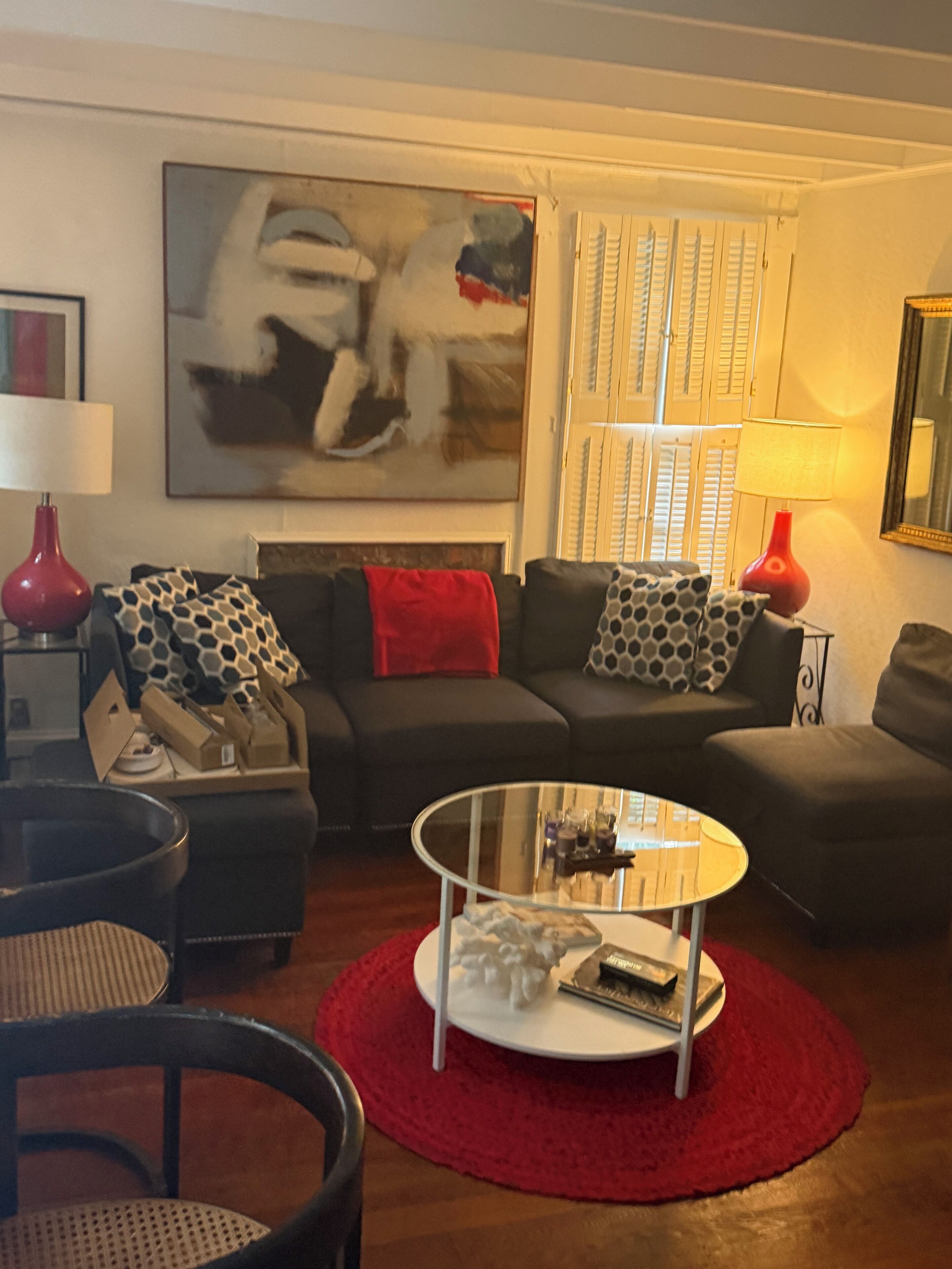 Un salon avec un canapé, une table basse en verre et un tapis rouge.