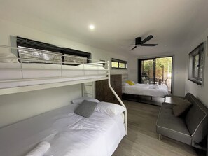 A modern, compact room with bunk beds, a sofa, and a ceiling fan. - River to the Sea - Jervis Bay (Myola)