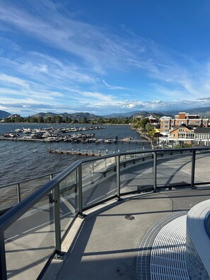 Een waterkantpromenade met een jachthaven, gebouwen en heuvels in de verte.