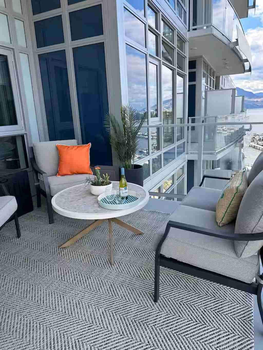 Ein Balkon mit rundem Tisch, Stühlen und einem Blumentopf.