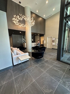 A modern lobby with a marble floor, a seating area with a sofa and chairs, a central table, and a unique chandelier. -     KELOWNA LUXURY LAKEVIEW ESCAPE WITH RESORT AMENITIES GALORE (Kelowna)
