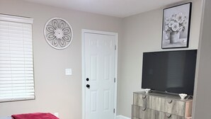 A bedroom with a bed, a ceiling fan, a door, a TV, and a cabinet. - 3-bedroom house in fabulous Winston-Salem with cool AC breeze (Winston-Salem)