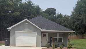 A single-story house with a garage, a front porch, and a small garden area. - 3-bedroom house in fabulous Winston-Salem with cool AC breeze (Winston-Salem)