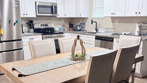 A modern kitchen with white cabinets, stainless steel appliances, and a dining area with a wooden table and chairs. - 3-bedroom house in fabulous Winston-Salem with cool AC breeze (Winston-Salem)