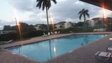 A swimming pool with lounge chairs and palm trees in the background.