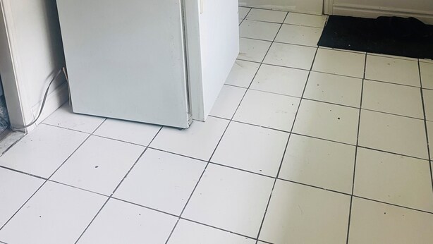 A white refrigerator with a jar of peanut butter on top, a door with a handle, and a tiled floor. - Apartment for rent (Toronto)