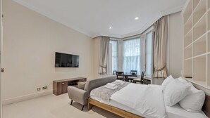 A modern bedroom with a bed, a TV, a desk, and a chair. - Modern Studio in Knightsbridge Greater London (London)
