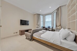 Ein modernes Schlafzimmer mit Bett, Fernseher, Schreibtisch und Stuhl.
