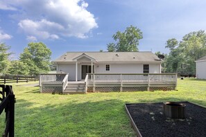 Einbungalow mit einer Veranda, einer kleinen Terrasse und einem Feuerkorb im Garten.