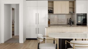 Una cucina moderna con mobili bianchi, un'isola centrale con posti a sedere e un frigorifero nero.