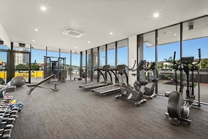 Ein Fitnessstudio mit Laufbändern, Crosstrainern und Kurzhanteln.