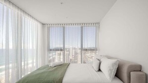 Una camera da letto con un letto, vista sulla città e tende leggere.