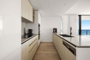 Eine moderne Küche mit Holzschränken, einer schwarzen Arbeitsplatte und einem Geschirrspüler.