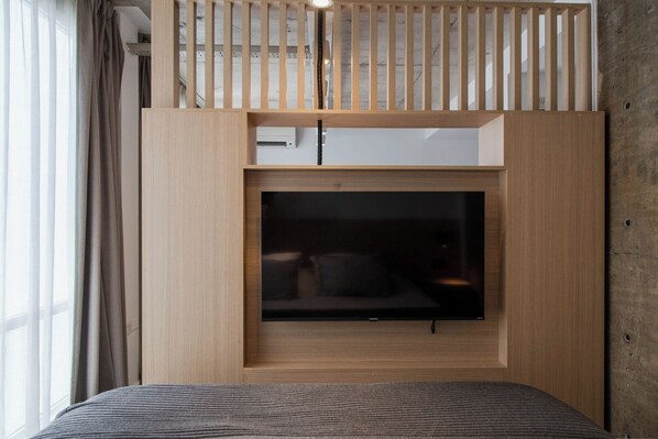 A room with a bed, a TV mounted on a wooden wall, and a window with curtains. - Recoleta Prime Location | New Studio - Coworking - BBQ (Buenos Aires)