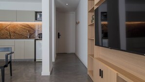 Una cuina moderna amb forn integrat, zona de menjador amb una cadira i un passadís que condueix a una porta.