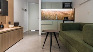 Une cuisine moderne équipée d’un four à micro-ondes encastré, d’une petite table ronde et d’un canapé vert.