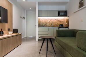 A modern kitchen with a built-in microwave, a small round table, and a green sofa. - Modern Recoleta Studio with BBQ Terrace and Coworking Space (Buenos Aires)