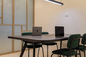 A conference room with a table, two laptops, and green chairs. - Modern Recoleta Studio with BBQ Terrace and Coworking Space (Buenos Aires)