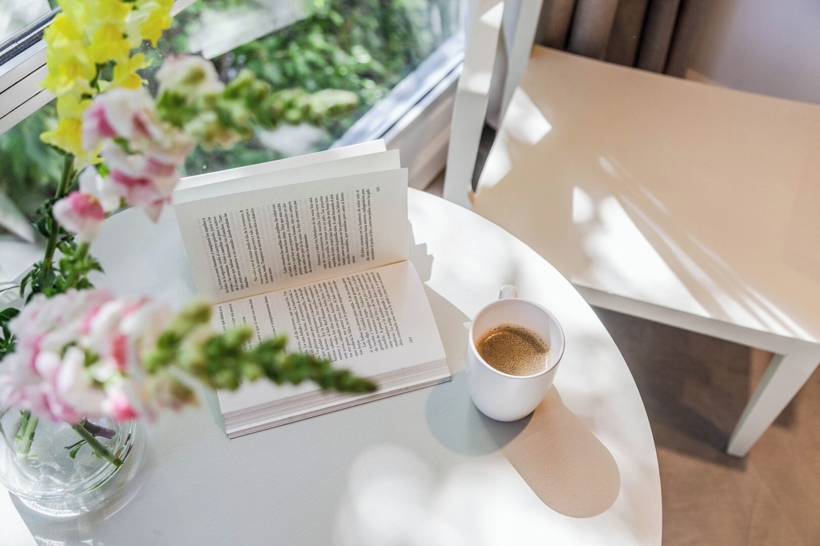 Un livre ouvert sur une table blanche, avec une tasse de café à côté.