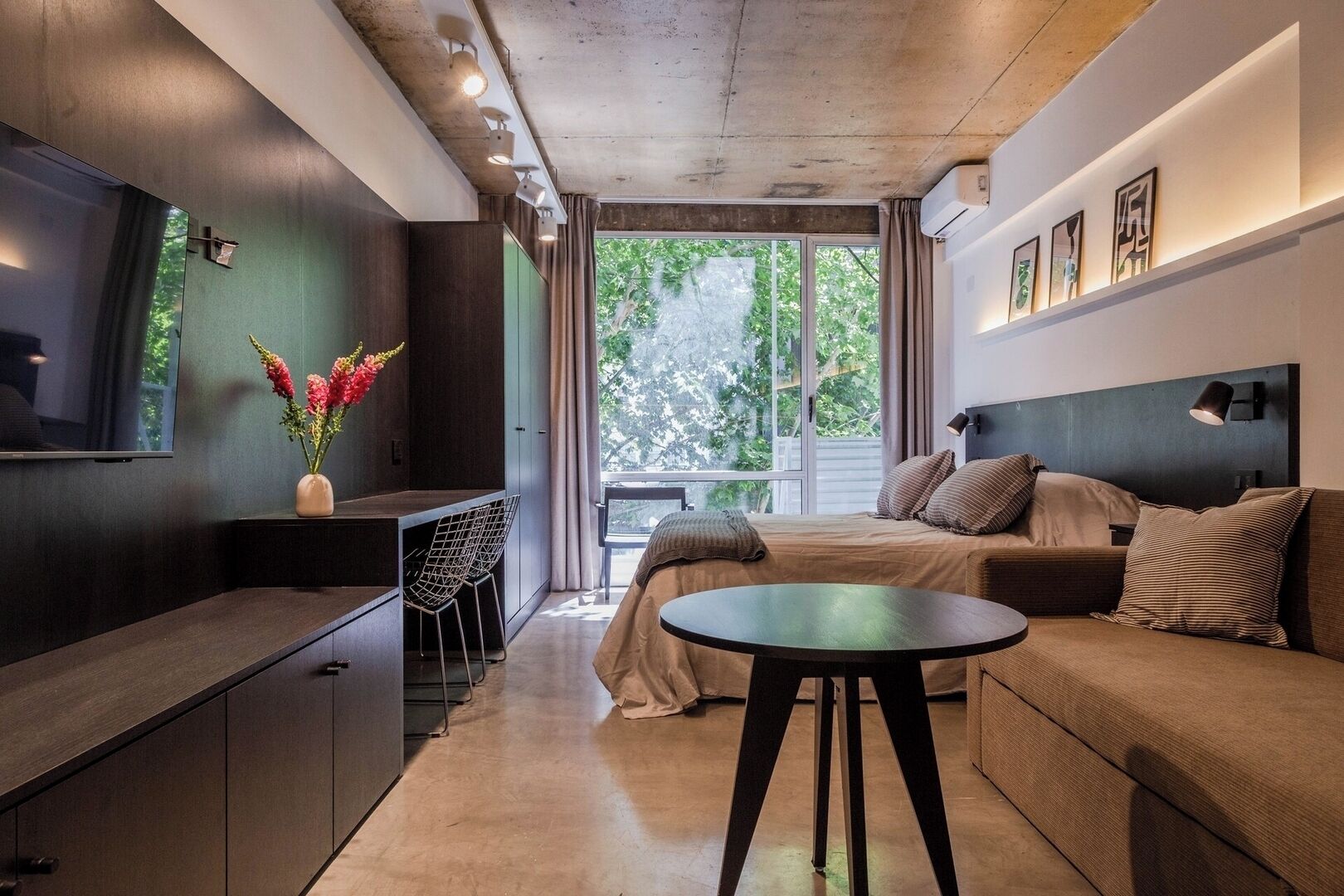 Une chambre d’hôtel moderne équipée d’un lit, d’un canapé, d’une télévision et d’un bureau avec une chaise.