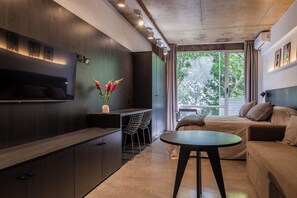 Ein modernes Interieur mit einem Bett, einem Sofa, einem Esstisch und einer Küchenzeile.