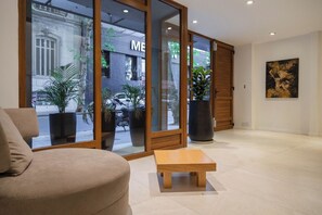 Ein modernes Interieur mit einer Couch, einem kleinen Holztisch und großen Fenstern mit Blick auf die Straße.