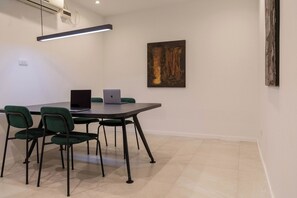 Ein Konferenzraum mit Tisch, Stühlen, zwei Laptops, einem Gemälde und einer Klimaanlage.