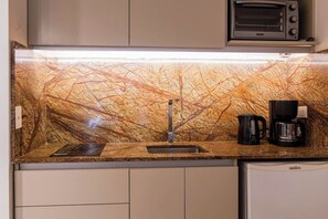 A kitchen with a marble backsplash, a built-in microwave, a coffee maker, and a dishwasher.