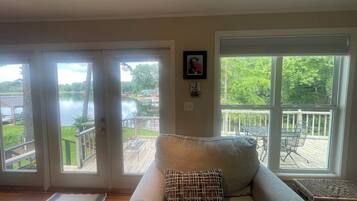A living room with a sofa, a view of a lake, and a deck.