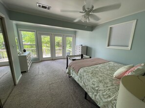 Een slaapkamer met een bed, een kapstok, een stoel en een plafondventilator.