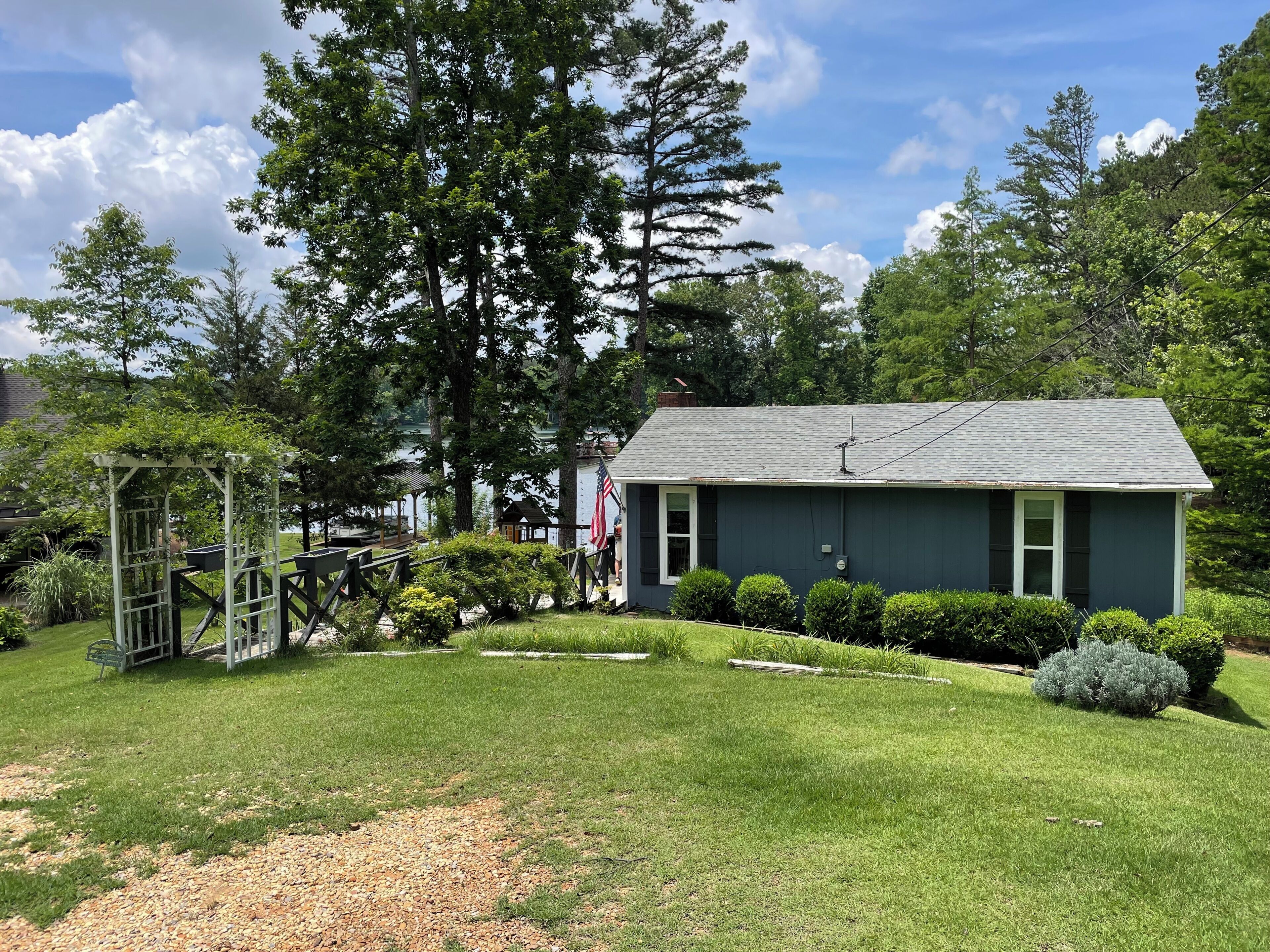 A house with a well-maintained lawn, a pergola, and a flag.