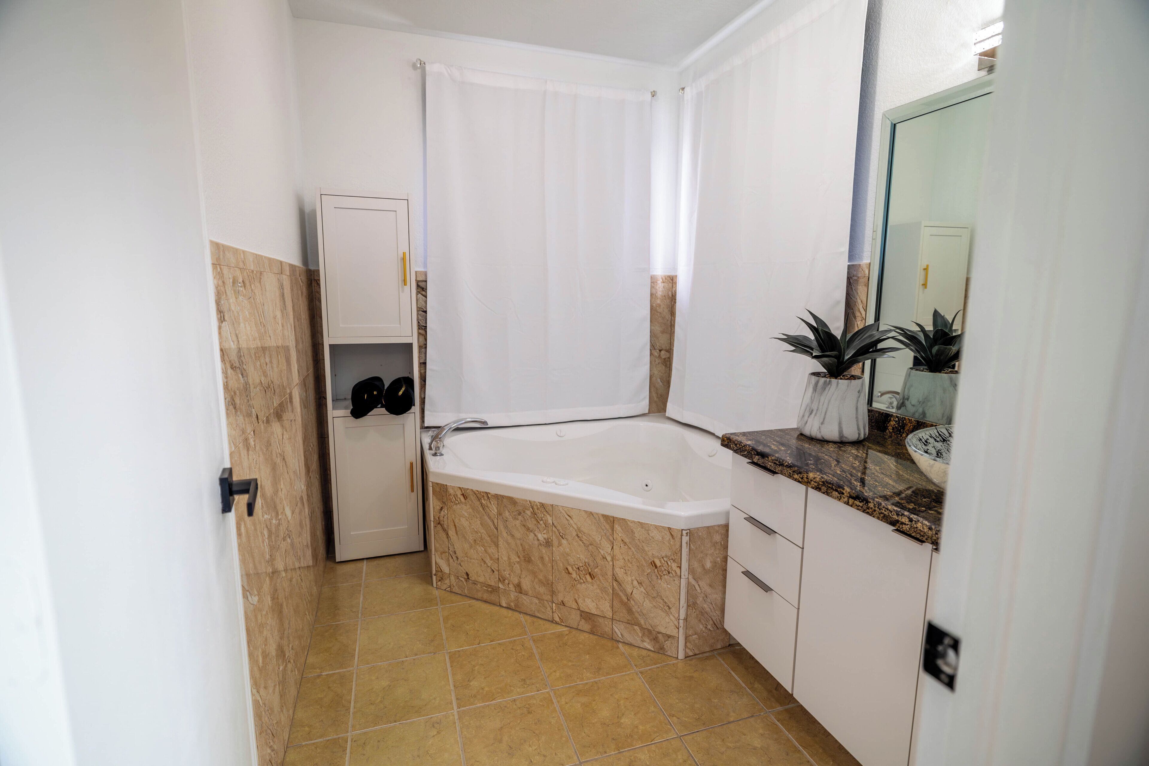 Ein Badezimmer mit einer Badewanne, einer Duschvorhang, einem Waschbecken mit Marmorplatte und einem Spiegel.