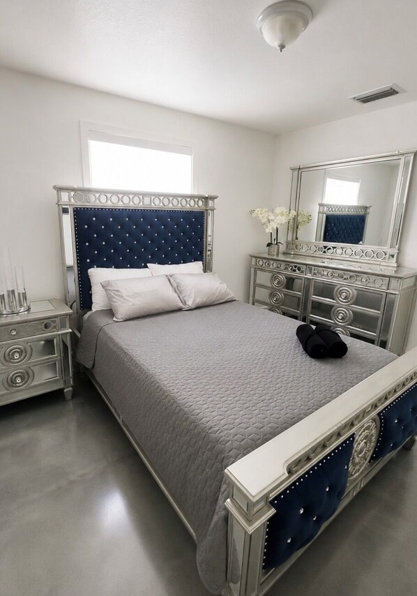 A bedroom with a bed, nightstands, a dresser, a mirror, and a ceiling light.