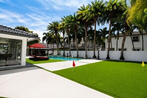 A modern house with a swimming pool, a covered patio, and a well-maintained lawn. - Nova Palm Estate, Pool, BBQ & Game Yard (Miami)