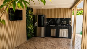 Una cocina moderna con refrigerador integrado, encimera negra y televisor montado en la pared.
