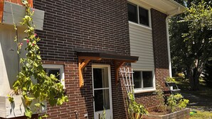 A brick house with a wooden porch, a window, and raised garden beds. - Cozy 1-bedroom apartment in lovely Weaverville with AC (Weaverville)