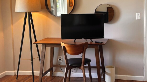 A room with a desk, a chair, a television, a lamp, and a mirror. - Cozy 1-bedroom apartment in lovely Weaverville with AC (Weaverville)