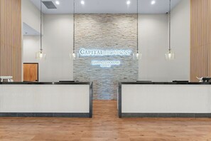 Ein Empfangsbereich mit Steinwand, zwei Empfangstresen, hängenden Pendelleuchten und einem Schild mit der Aufschrift 'Capitalvacations Grand Crowne Resort'.
